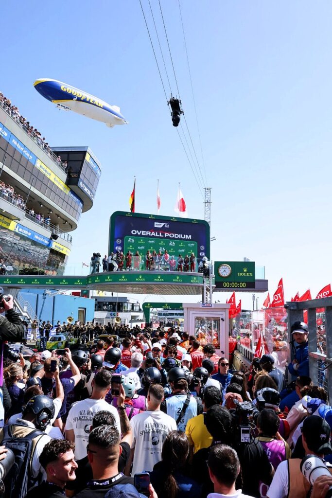 Fans watch the 2026 Le Mans victory ceremony from the podium area