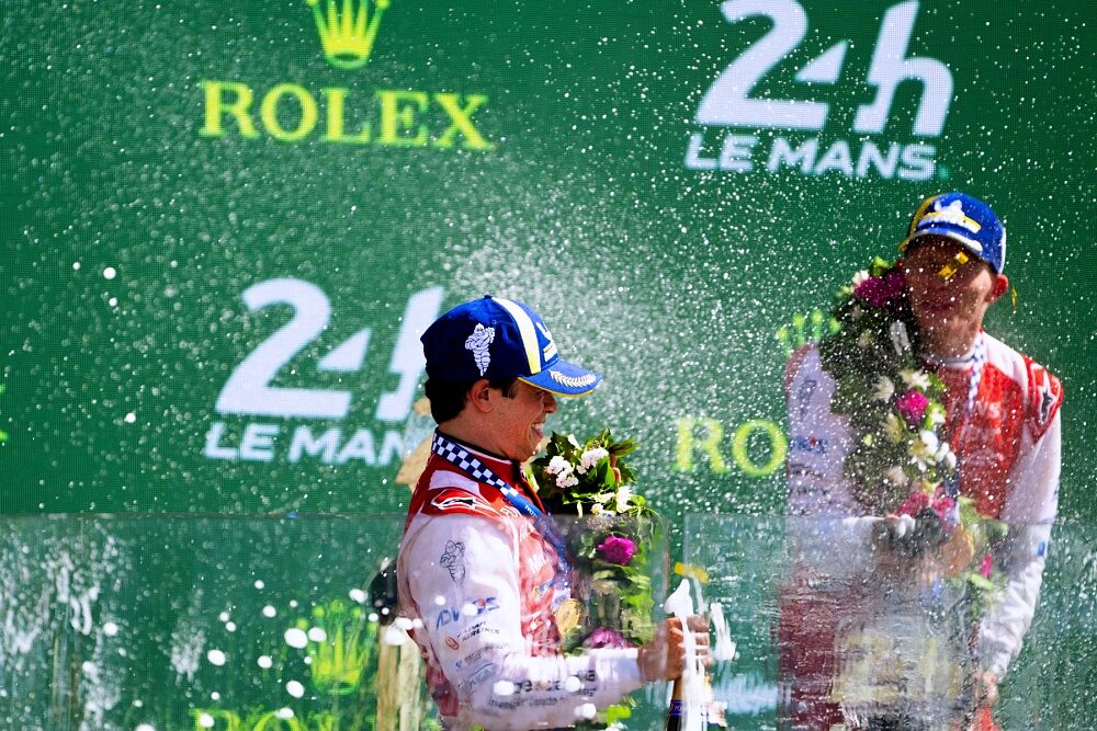 Toyota Racing driver celebrates with champagne on the Le Mans podium