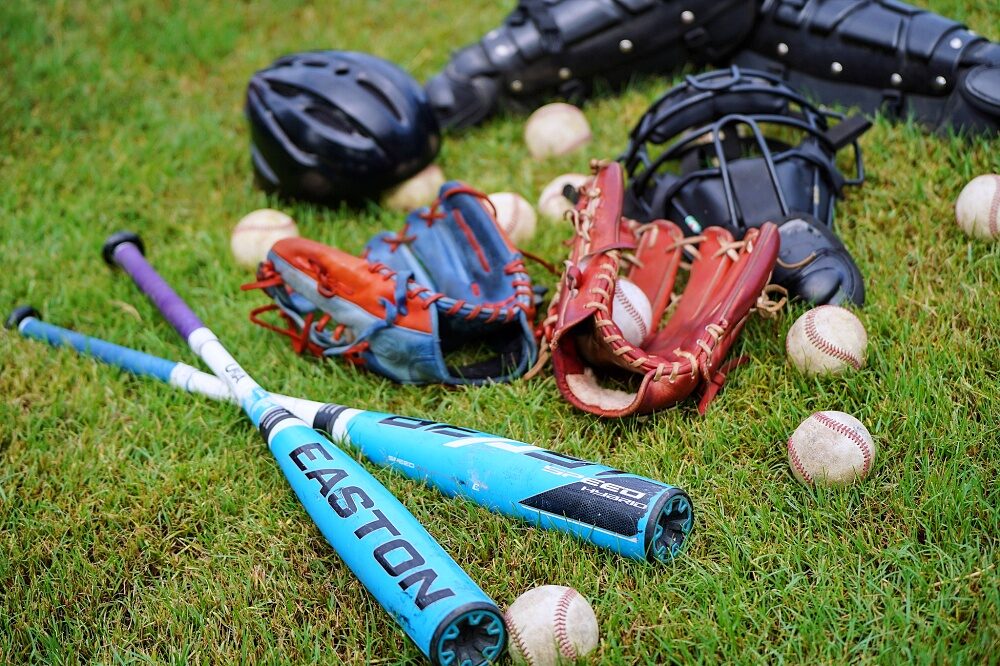 Baseball gloves, bats and balls arranged on the field