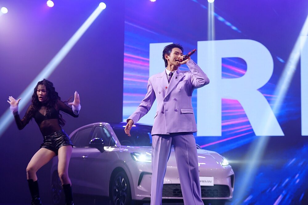 ภาพโชว์ร้องเพลงสดของศิลปินข้างรถยนต์ไฟฟ้า MG URBAN 2026 สีชมพูลาเวนเดอร์