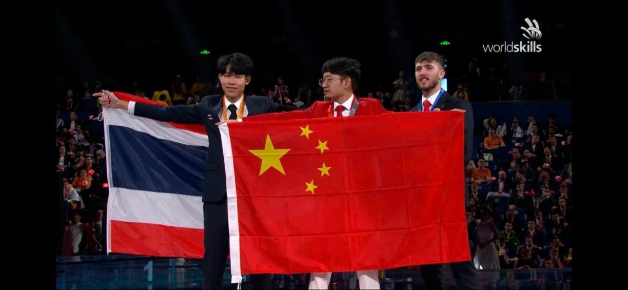 ผู้เข้าแข่งขันชาวไทยและจีนชูธงชาติบนเวทีมอบรางวัล WorldSkills