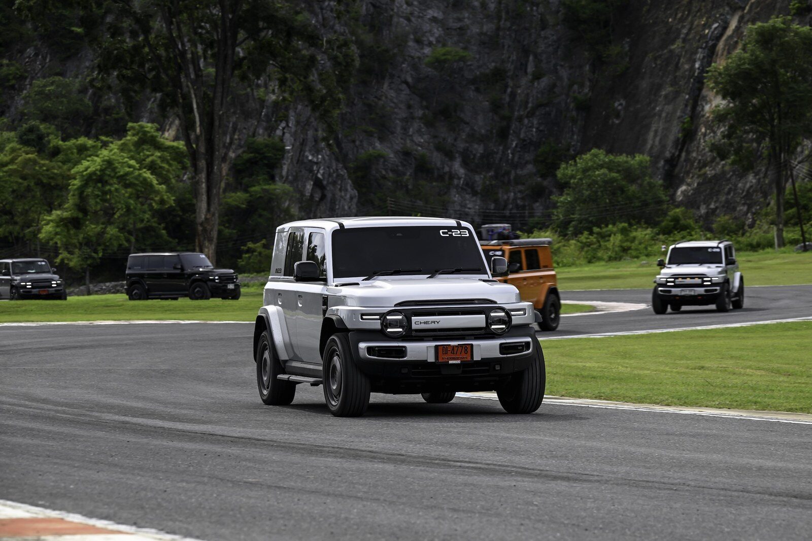 รถ SUV เชอรีสีขาววิ่งบนสนามแข่ง มีรถอีกหลายคันตามหลัง