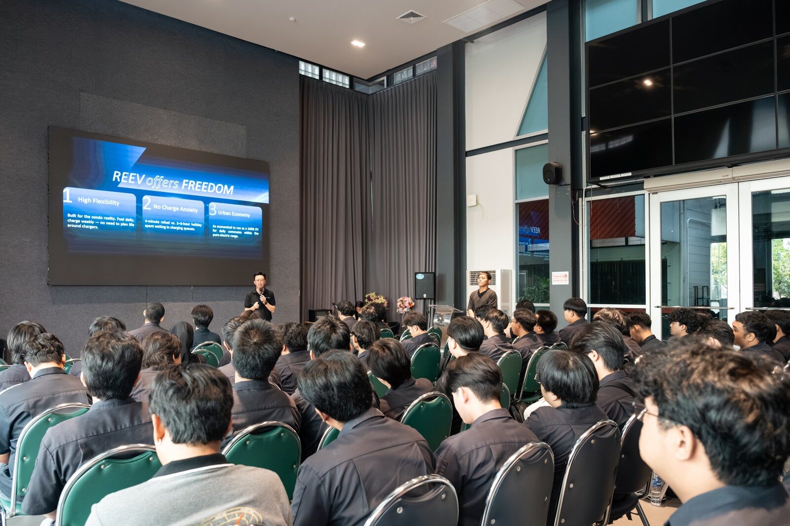 ห้องบรรยายที่นักศึกษานั่งฟังวิทยากรหน้าจอสไลด์ REEV offers FREEDOM