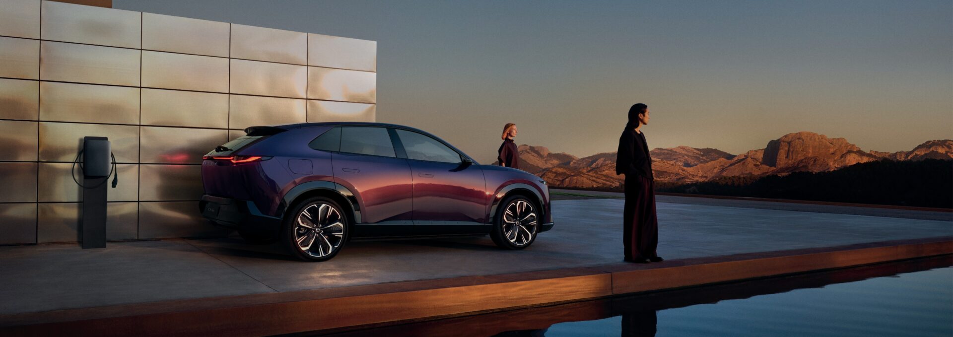 Mazda CX-6e มุมข้างจอดข้างแท่นชาร์จติดผนัง