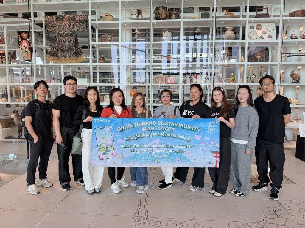 ผู้ร่วมกิจกรรมยืนถือป้ายกิจกรรมหน้าชั้นจัดแสดงสิ่งของในพิพิธภัณฑ์