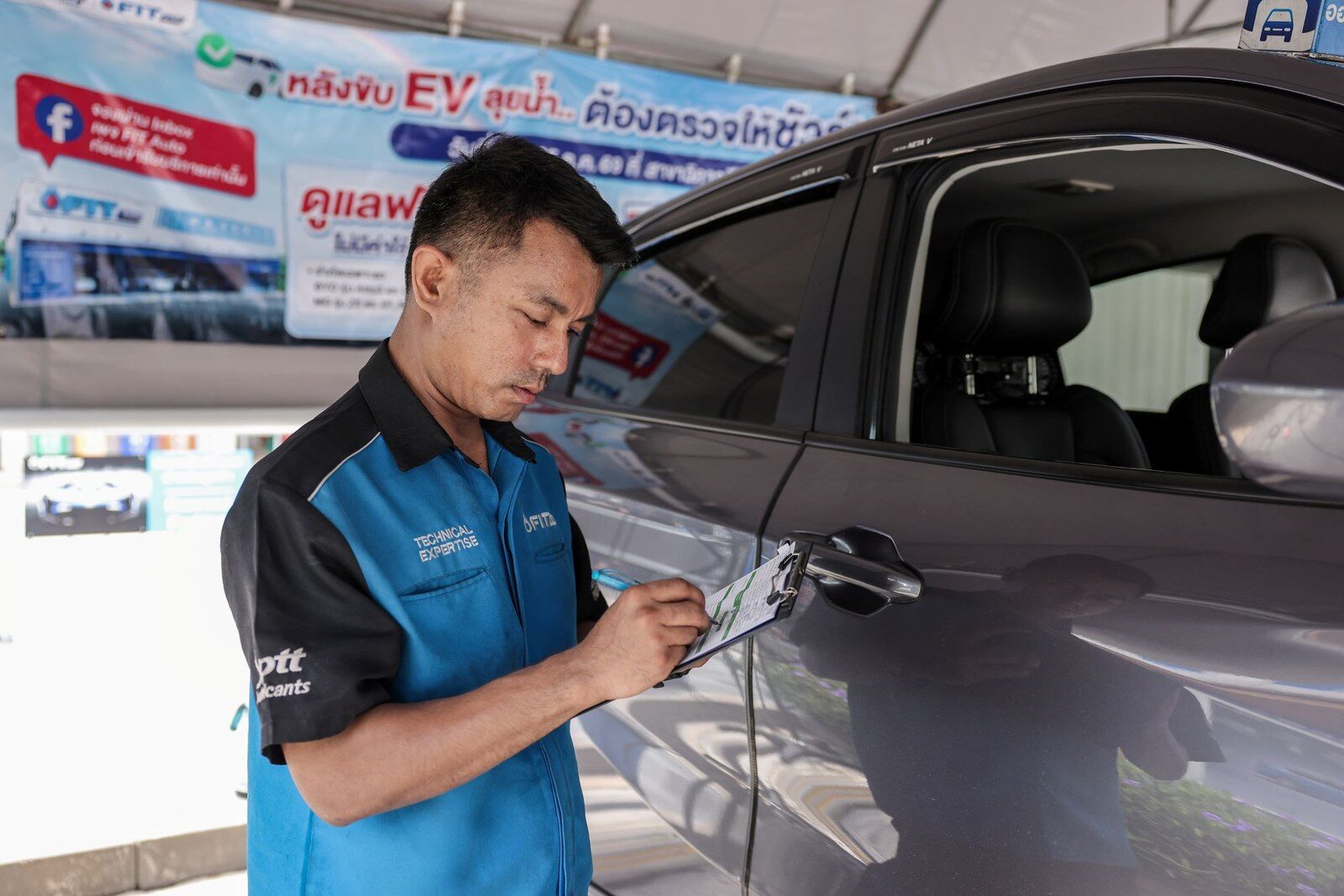 ช่าง FIT Auto จดข้อมูลบนคลิปบอร์ดข้างตัวรถ