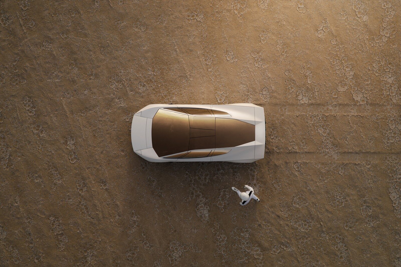 ภาพมุมสูงของ Roadster สีขาวพร้อมกระจกหลังคาย้อมสีทองบนพื้นทะเลทราย