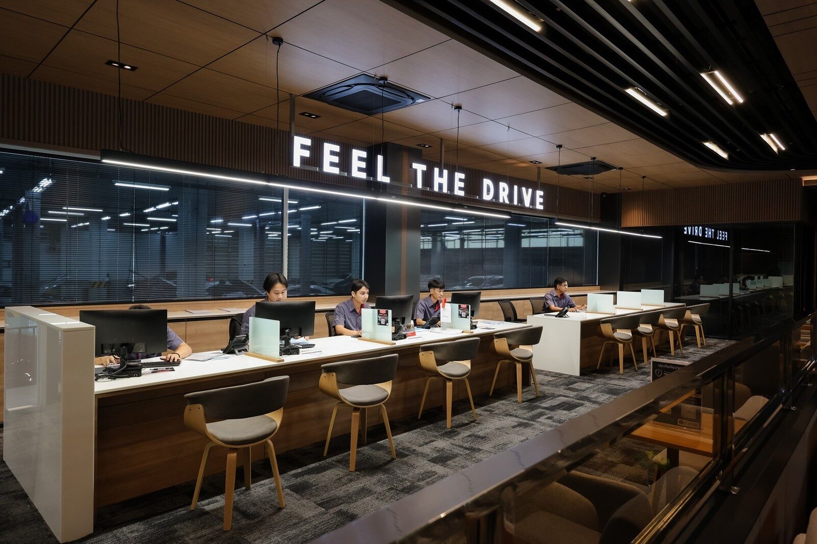 เคาน์เตอร์ยาวที่มีเจ้าหน้าที่นั่งปฏิบัติงานใต้ป้ายไฟ FEEL THE DRIVE