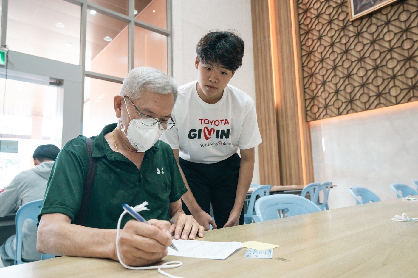 นักเรียนทุนมูลนิธิโตโยต้าประเทศไทยช่วยผู้สูงอายุกรอกเอกสารลงทะเบียน
