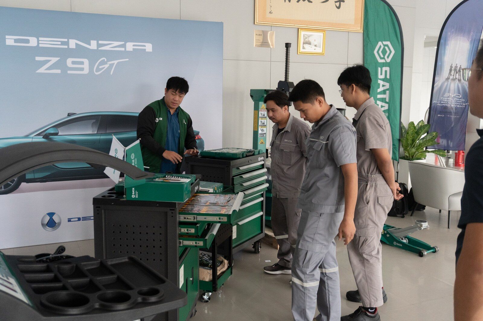 ผู้เข้าแข่งขันดูชุดเครื่องมือช่างหน้าฉากหลังป้าย DENZA Z9 GT