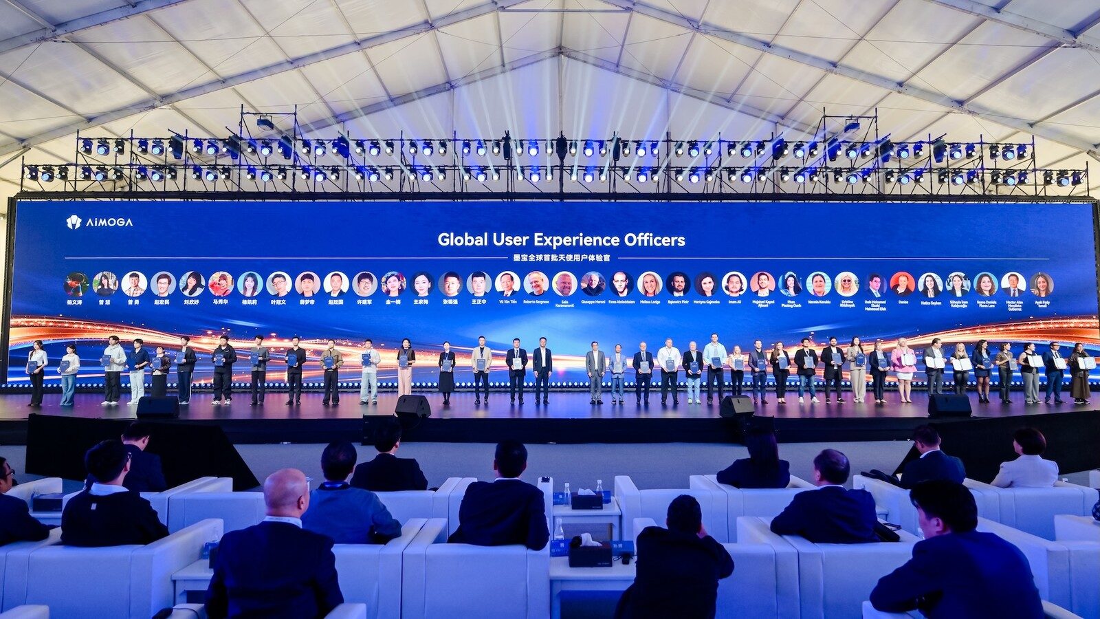 ผู้ร่วมงานยืนบนเวทีช่วง Global User Experience Officers ในงานเปิดตัว AiMOGA