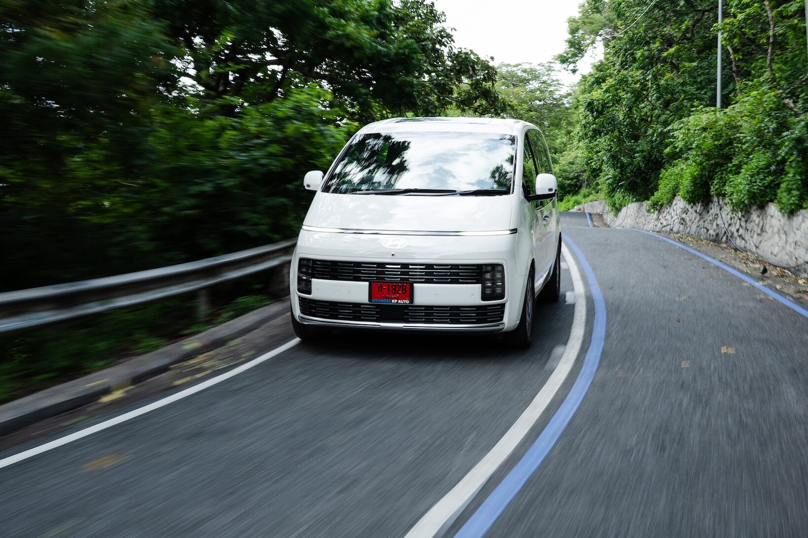 Hyundai STARIA Hybrid 2026 สีขาว เข้าโค้งบนถนนเลียบเขา