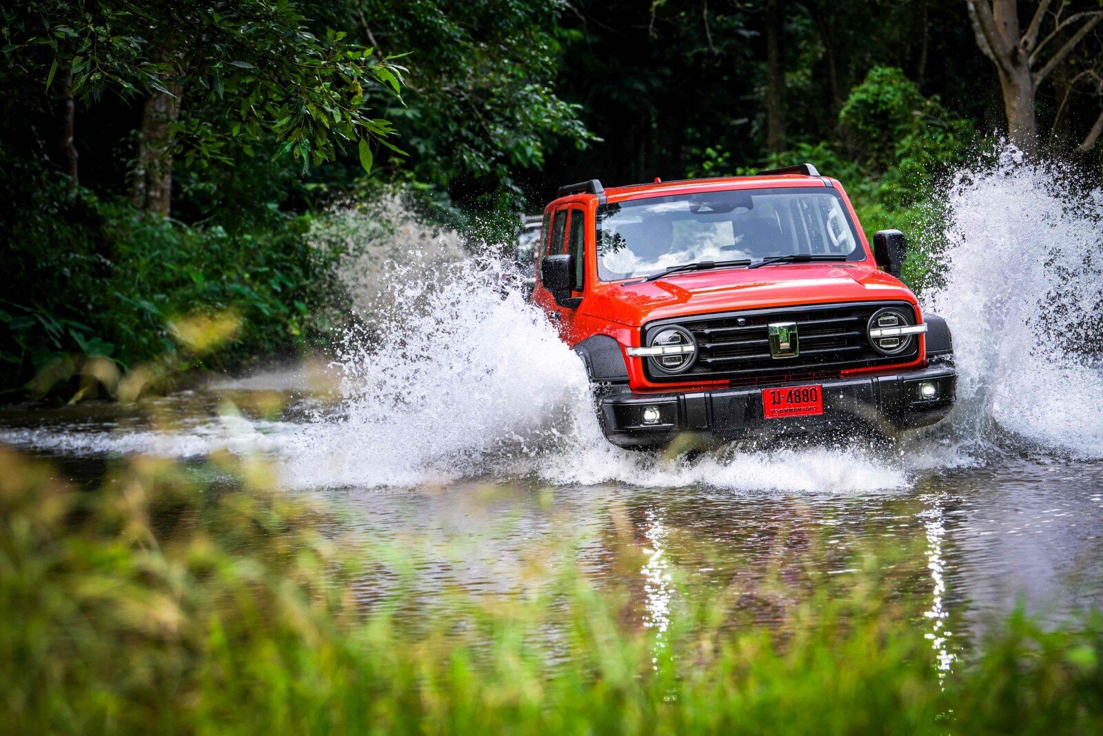 รถ GWM TANK สีส้มลุยน้ำจนน้ำกระเซ็นกลางป่า
