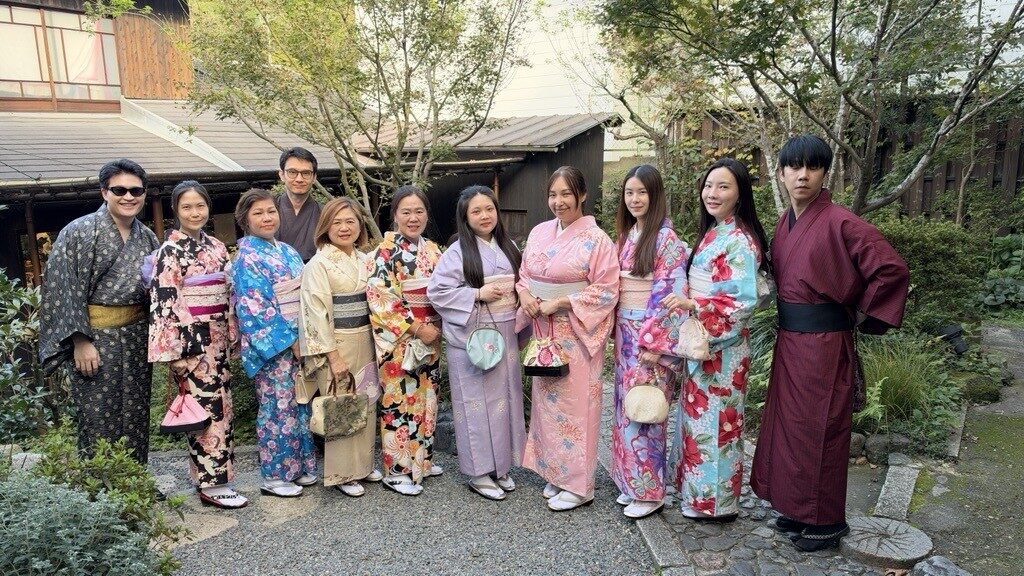 ผู้ร่วมเดินทางในชุดกิโมโนยืนถ่ายภาพในสวนญี่ปุ่น