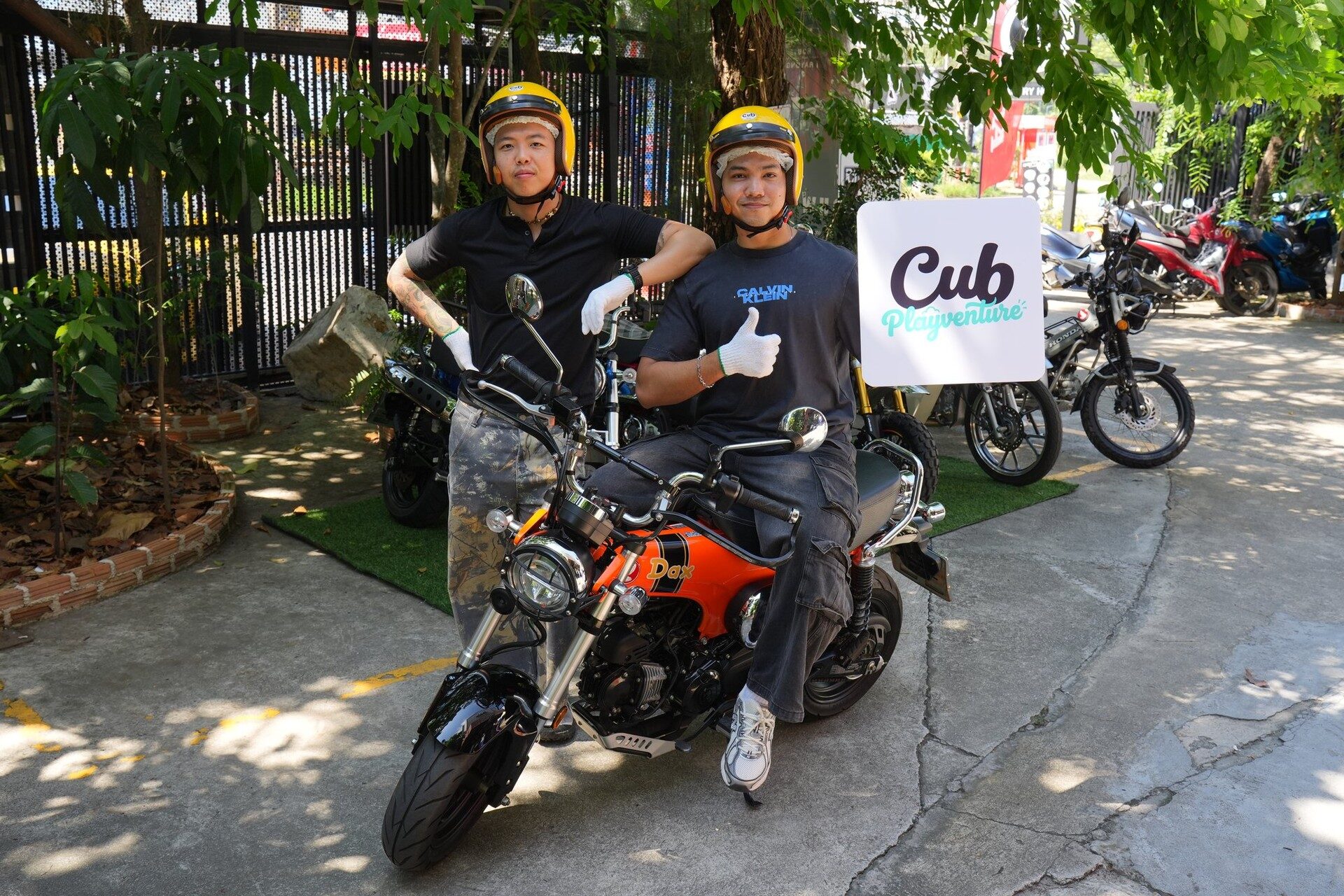 ผู้ร่วมทริปสองคนนั่งบนรถ Honda Dax สีส้มพร้อมป้าย Cub Playventure
