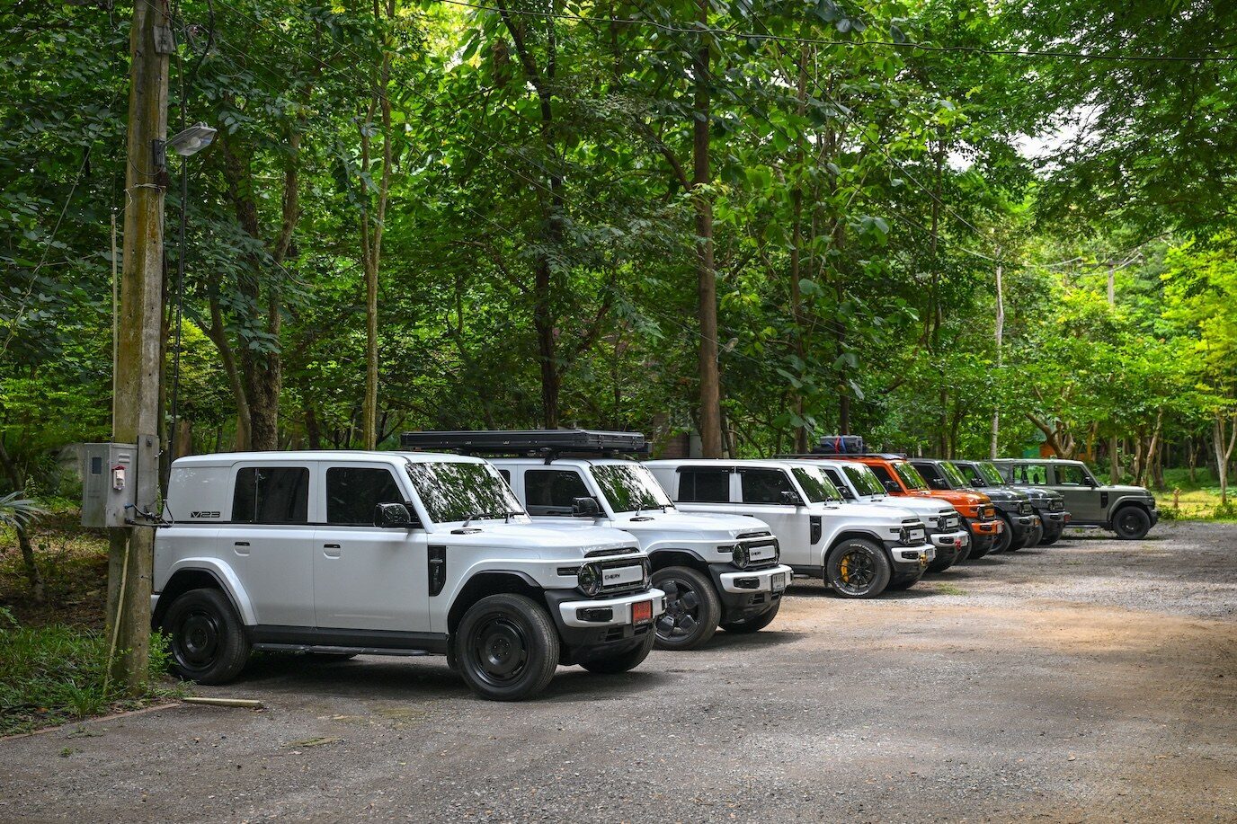 รถ SUV เชอรีหลายคันจอดเรียงแถวใต้ร่มไม้ริมทางลูกรัง