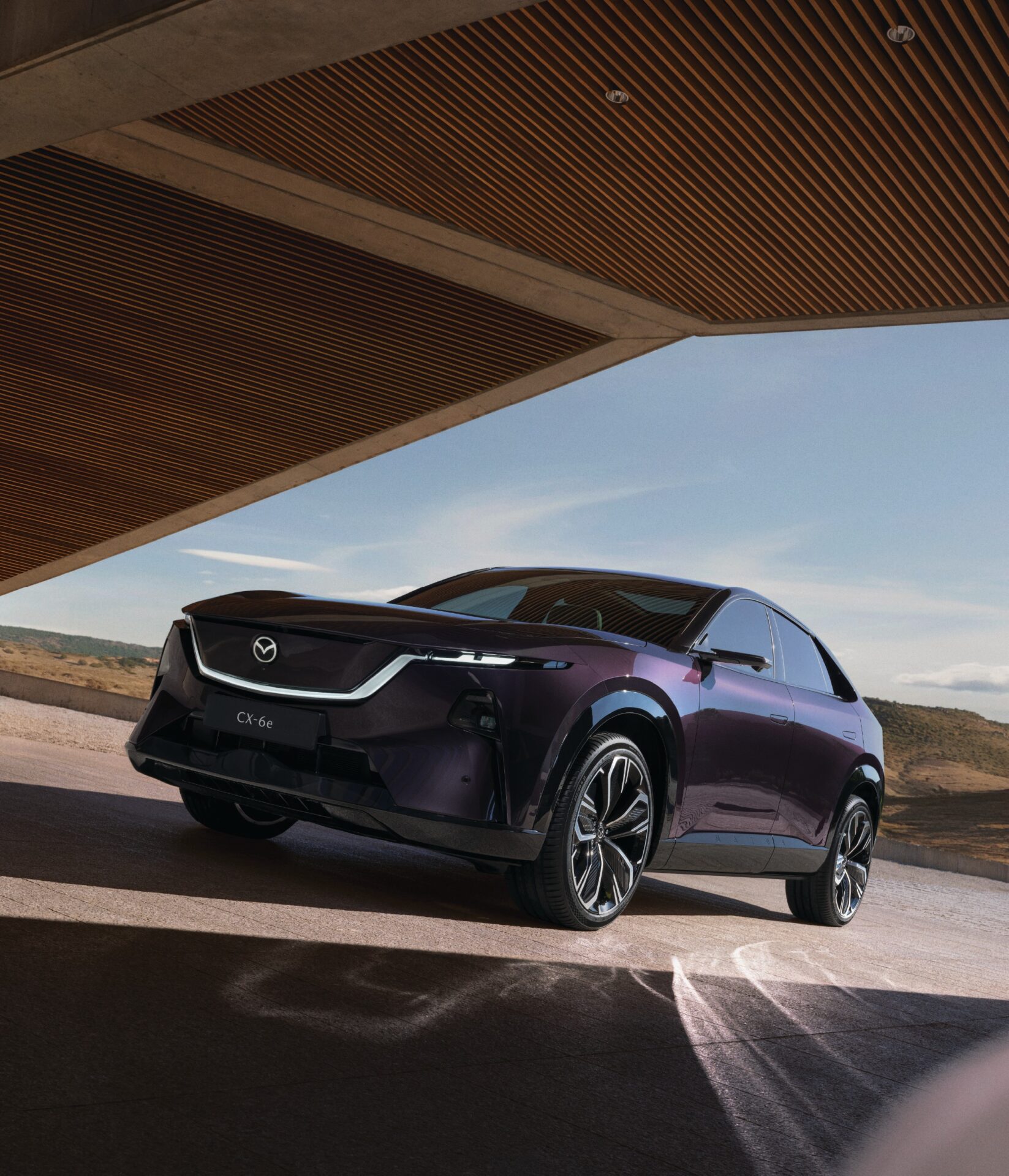 Mazda CX-6e สีม่วงเข้มมุมหน้าเฉียงใต้หลังคาอาคาร