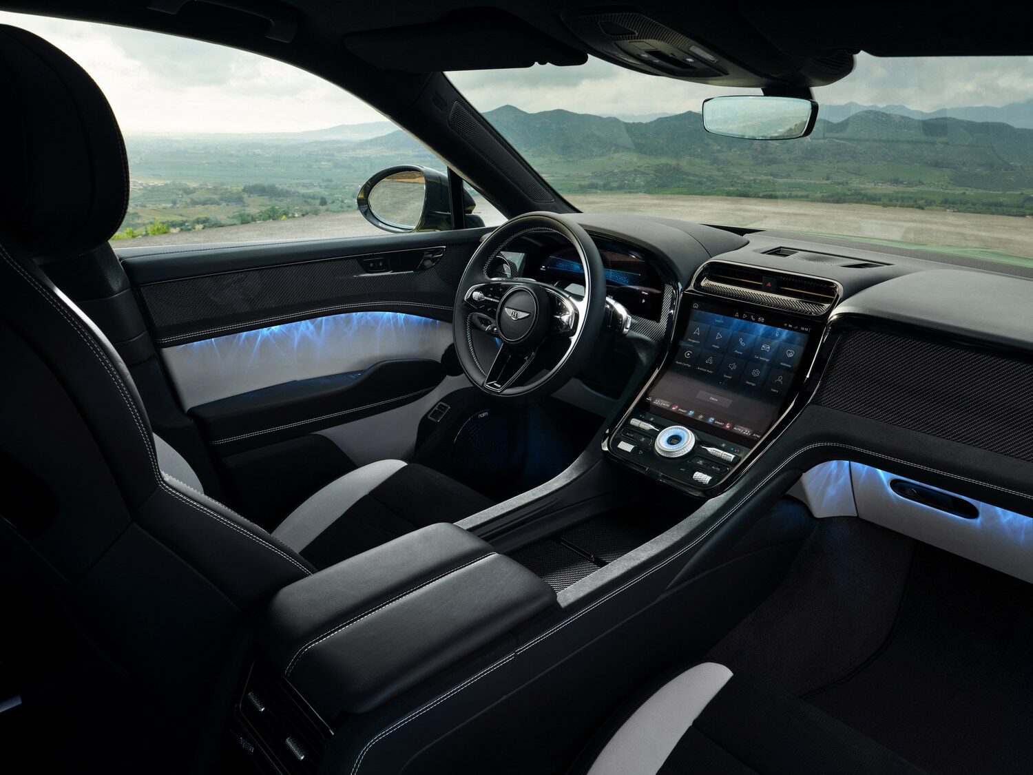 ห้องโดยสารตอนหน้าของ Bentley Torcal เห็นพวงมาลัย หน้าจอกลาง และไฟตกแต่งสีฟ้า