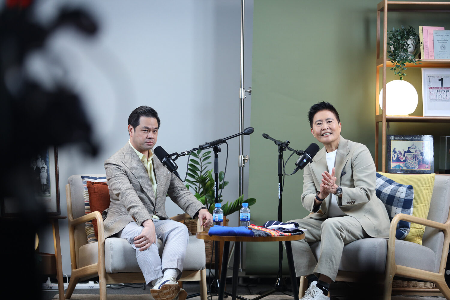 พิธีกรและแขกรับเชิญนั่งสนทนาหน้าไมโครโฟนในสตูดิโอรายการ