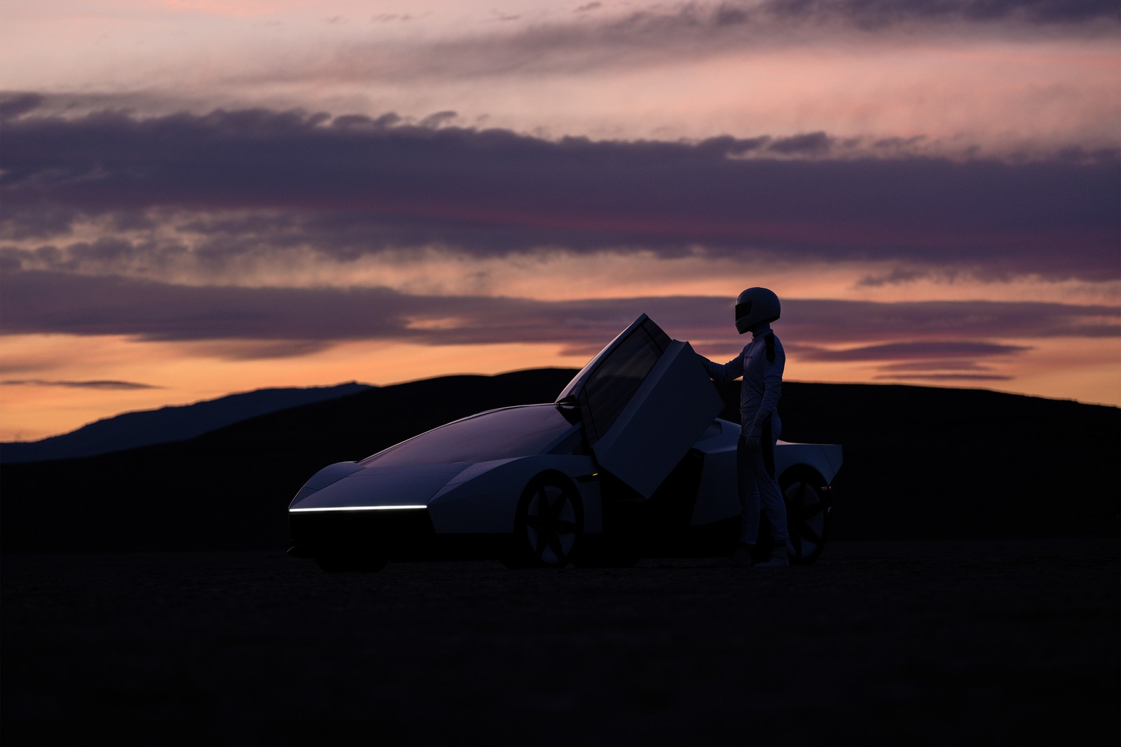 เงาของ Roadster ที่ยกประตูขึ้น มีผู้สวมชุดและหมวกนิรภัยยืนข้างรถยามพลบค่ำ