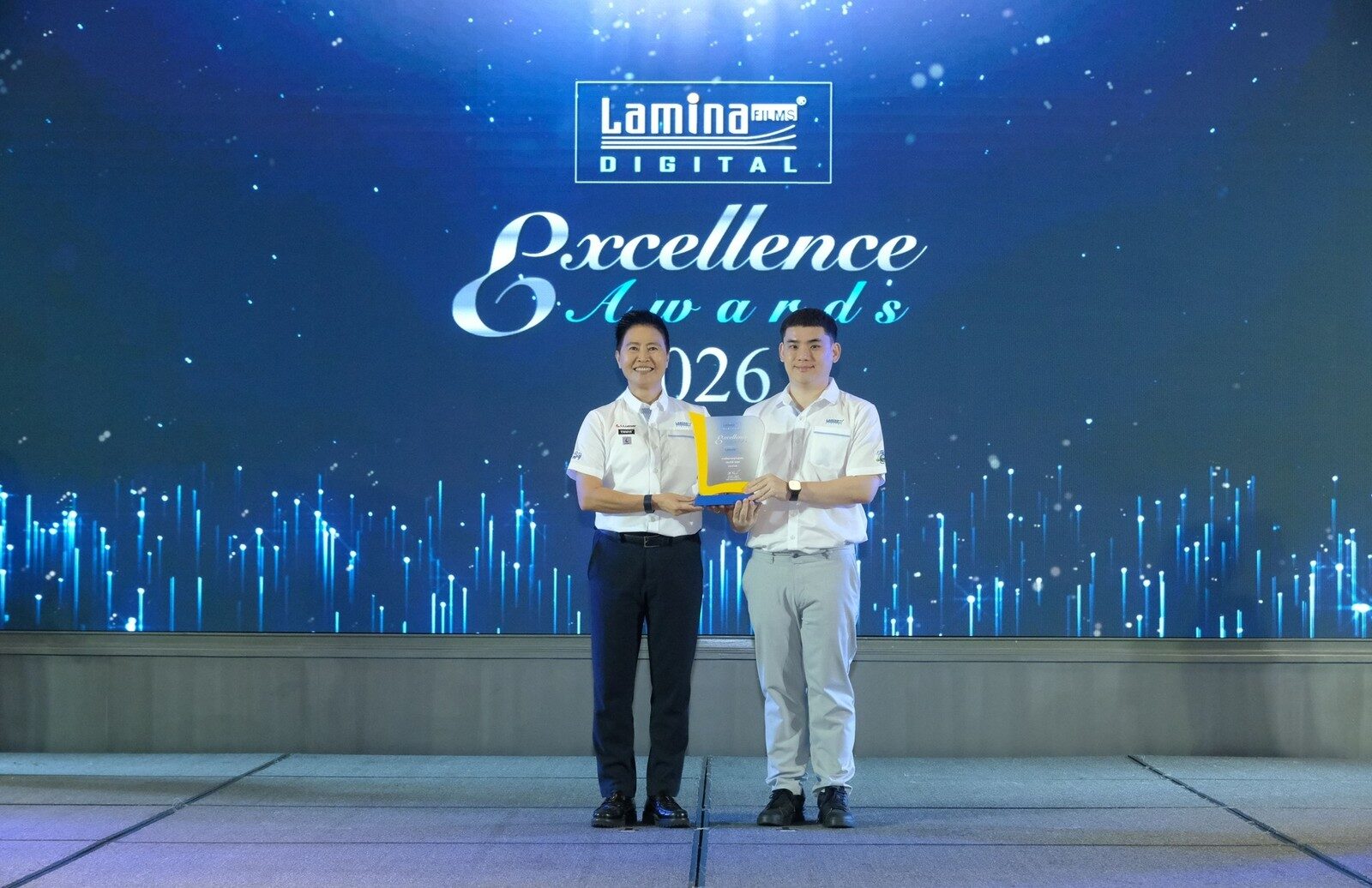 ผู้บริหารยื่นโล่รางวัลให้ตัวแทนศูนย์จำหน่ายบนเวที Lamina Excellence Awards 2026
